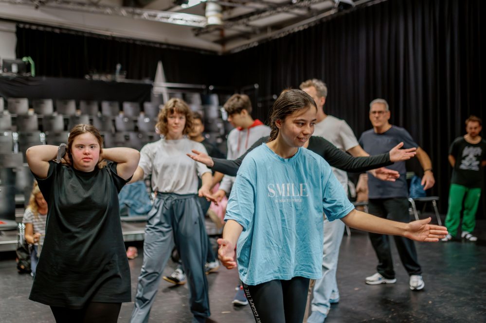 Eine Gruppe von Menschen nimmt an einem Tanzkurs teil und übt verschiedene Tanzbewegungen gemeinsam.