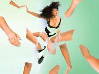 Amrinta Hepi ist in einen hellen grünen Hintergrund eingebettet. Sie scheint sich dynamisch zu bewegen und gleichzeitig zu schweben. Ihre Beine und ein Arm sind durchsichtig retouschiert und nur durch die Umrisse zu erkennen. Dafür wurden durch Bildbearbeitung viele lose Arme und Beine hinzugefügt, die sich frei im Bild zu bewegen scheinen.