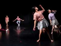 Kinder/Jugendliche in unterschiedlichen Positionen und Bewegungen in einem schwarzen Bühnenraum